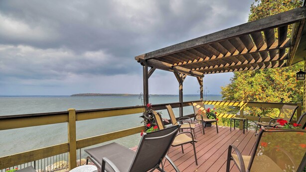 A wooden deck with outdoor seating and a view of the water. - Lake Champlain Cottage w/ Private Deck & Fire Pit! (North Hero)