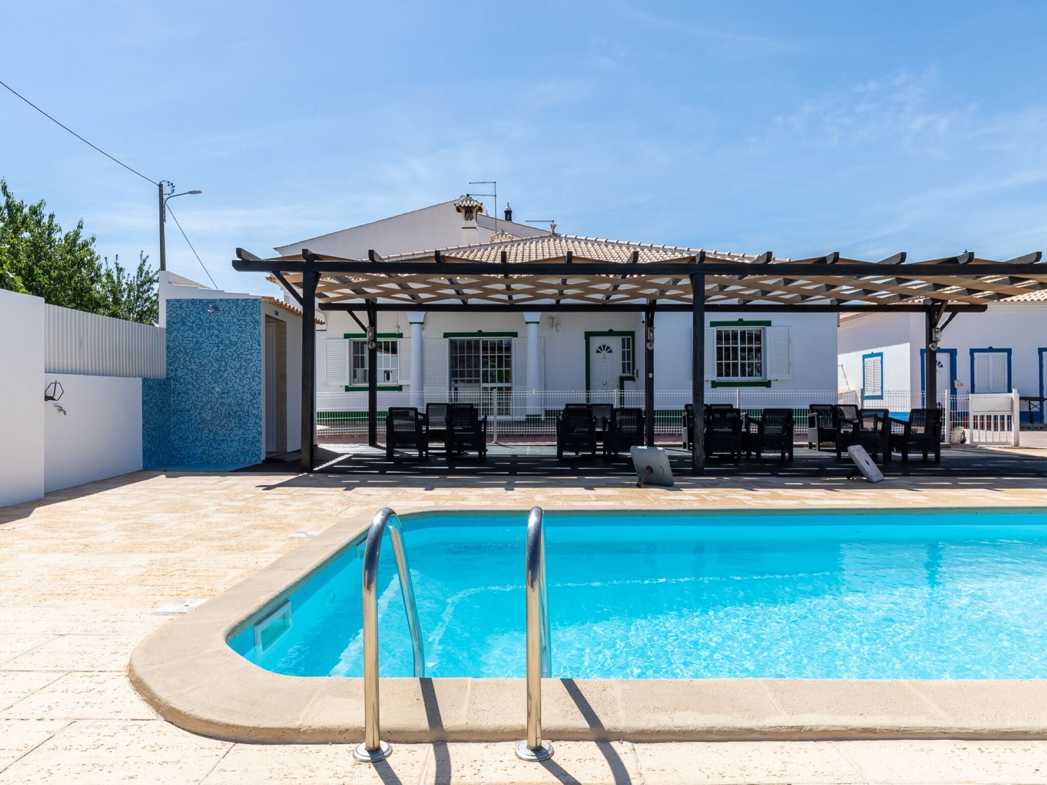 A swimming pool with a pergola and lounge chairs in a sunny outdoor area.