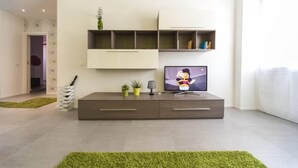 Un salon moderne doté d’un téléviseur à écran plat, d’étagères intégrées et d’un design minimaliste.
