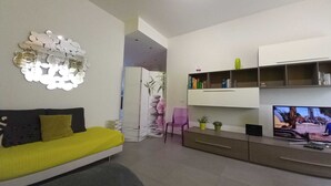 Un salon moderne avec un canapé, un téléviseur et un élément décoratif mural.