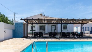 A swimming pool with a pergola and lounge chairs in a sunny outdoor area.