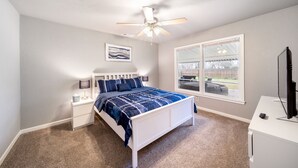 A bedroom with a bed, nightstands, a ceiling fan, a window, and a TV. - 4 bedroom house near, 15 min from Magnolia (Waco)
