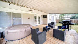 An outdoor patio with a covered area, a hot tub, wicker furniture, and a grill. - 4 bedroom house near, 15 min from Magnolia (Waco)