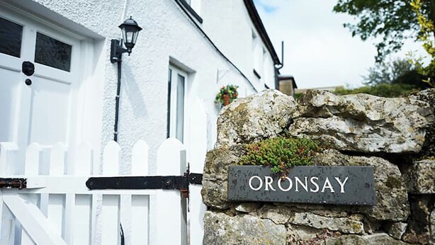 A white house with a stone wall and a sign that reads "ORONSAY". - A beautiful family holiday cottage with lots of character in an idyllic village (Ulverston)