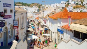 A bustling street with white buildings, a Coca-Cola sign, and a restaurant named "Super Bock".