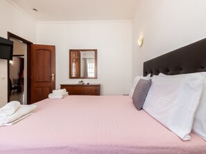A bedroom with a bed, a dresser, a mirror, and a wall-mounted light.