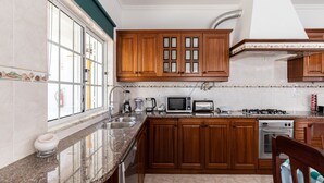 Una cocina con armarios de madera, microondas integrado, estufa a gas y lavavajillas.