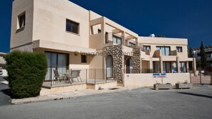 Un edificio moderno de dos pisos con fachada de piedra, un balcón y un letrero que indica prohibido estacionar.