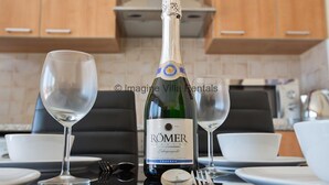 Una botella de vino RÖMER, dos copas de vino y una mesa de comedor con platos y cubiertos.