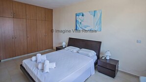 Un dormitorio con una cama, dos mesitas de noche, una cómoda y un armario grande.