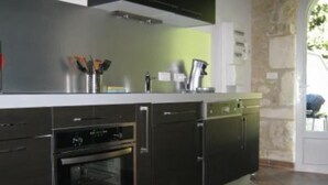 Een moderne keuken met zwarte apparaten, een wit aanrecht en een stenen muur.