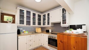 Een keuken met witte kasten, een inbouwoven en een magnetron.