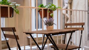 Une table et des chaises en bois sur un balcon, avec des plantes en pot.