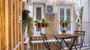 Un balcon doté de meubles en bois, de plantes en pot et d’un climatiseur blanc.