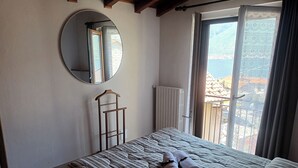 Une chambre à coucher avec un lit, un miroir rond, un radiateur et une vue sur l’extérieur.