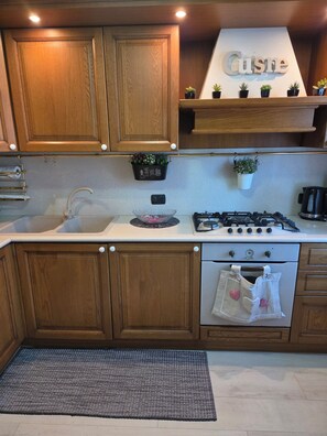 A kitchen with wooden cabinets, a gas stove, a sink, and a countertop with a backsplash.