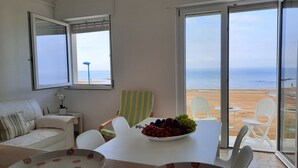 Una habitación con una mesa de comedor, sillas, un sofá y vista a la playa.