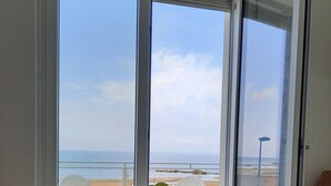 Una mesa con frutero en una habitación con ventanas amplias vistas al mar.