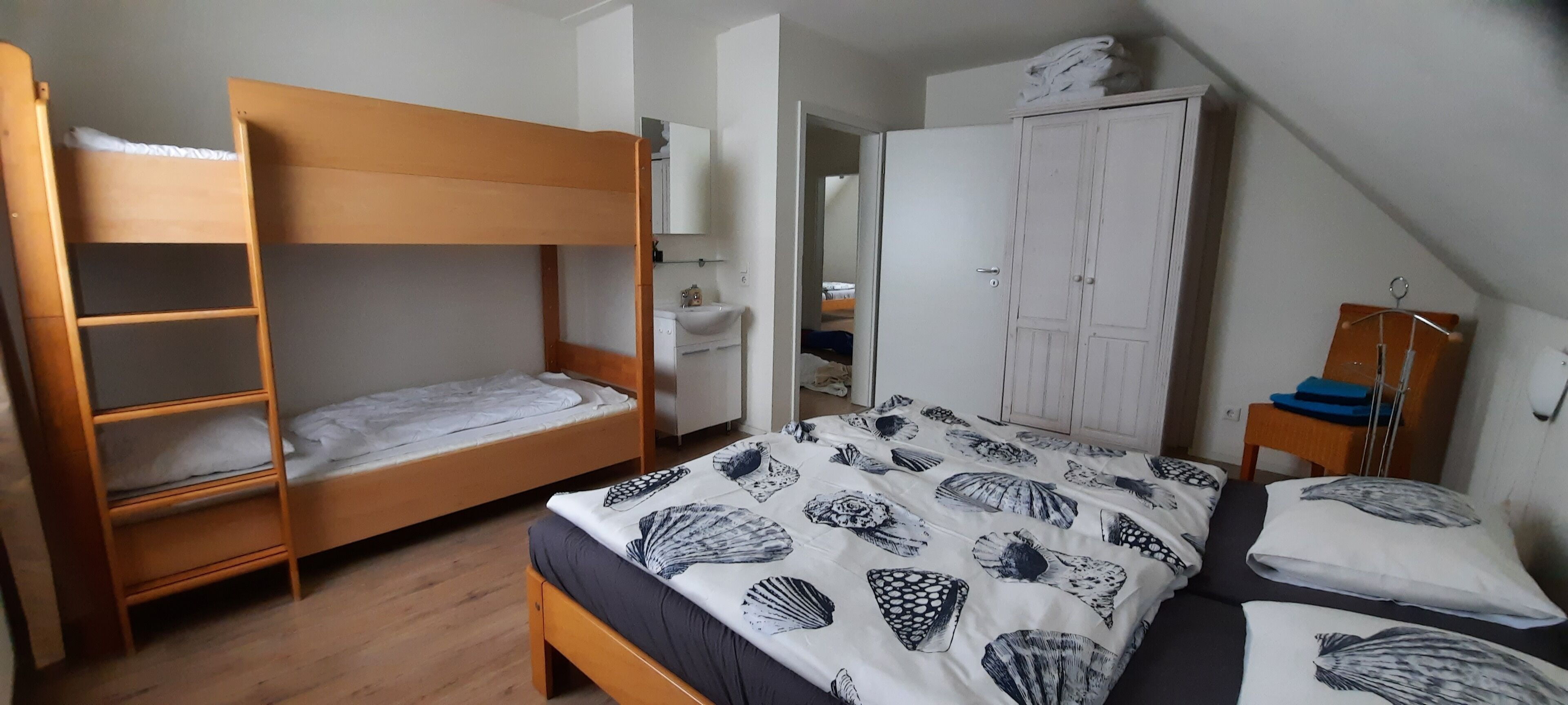Habitación tipo dormitorio con literas, un armario, un escritorio y un baño a la vista.