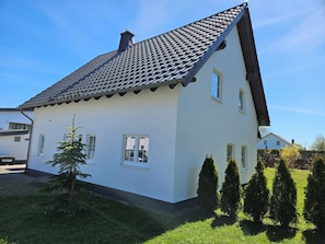 A two-story house with a tiled roof, white walls, and a small front yard with a tree and shrubs. - Directly in Winterberg, ski lift carousel 300m, bike park approx. 500m, center 1200m (Winterberg)