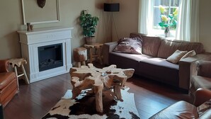 A living room with a fireplace, a sofa, a coffee table, and a cowhide rug.