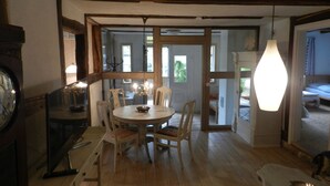A dining area with a round table and chairs, a chandelier, and a wooden ceiling. - Romantic located, historic water mill in Silberbachtal (Horn-Bad Meinberg)