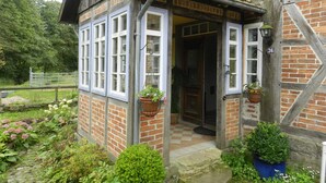 A traditional brick house with a small porch, white-framed windows, and a number '36' sign. - Romantic located, historic water mill in Silberbachtal (Horn-Bad Meinberg)