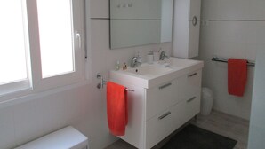 A bathroom with a white sink, mirror, and cabinet, a toilet, and a red towel hanging on a rack. - “Ampolla Villa”, 5 min away from the beach, 500 sqm garden, 9 persons (L' AMPOLLA)
