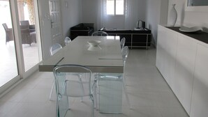 Een moderne keuken met een groot eiland, transparante stoelen en een eettafel.