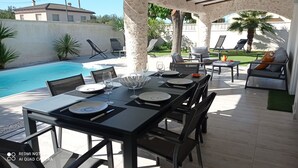 An outdoor dining area with a pool, tables set for four, and lounge chairs. - “Ampolla Villa”, 5 min away from the beach, 500 sqm garden, 9 persons (L' AMPOLLA)