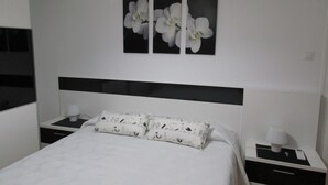 A hotel room with a bed, a nightstand, a lamp, and a wall-mounted air conditioning unit. - “Ampolla Villa”, 5 min away from the beach, 500 sqm garden, 9 persons (L' AMPOLLA)