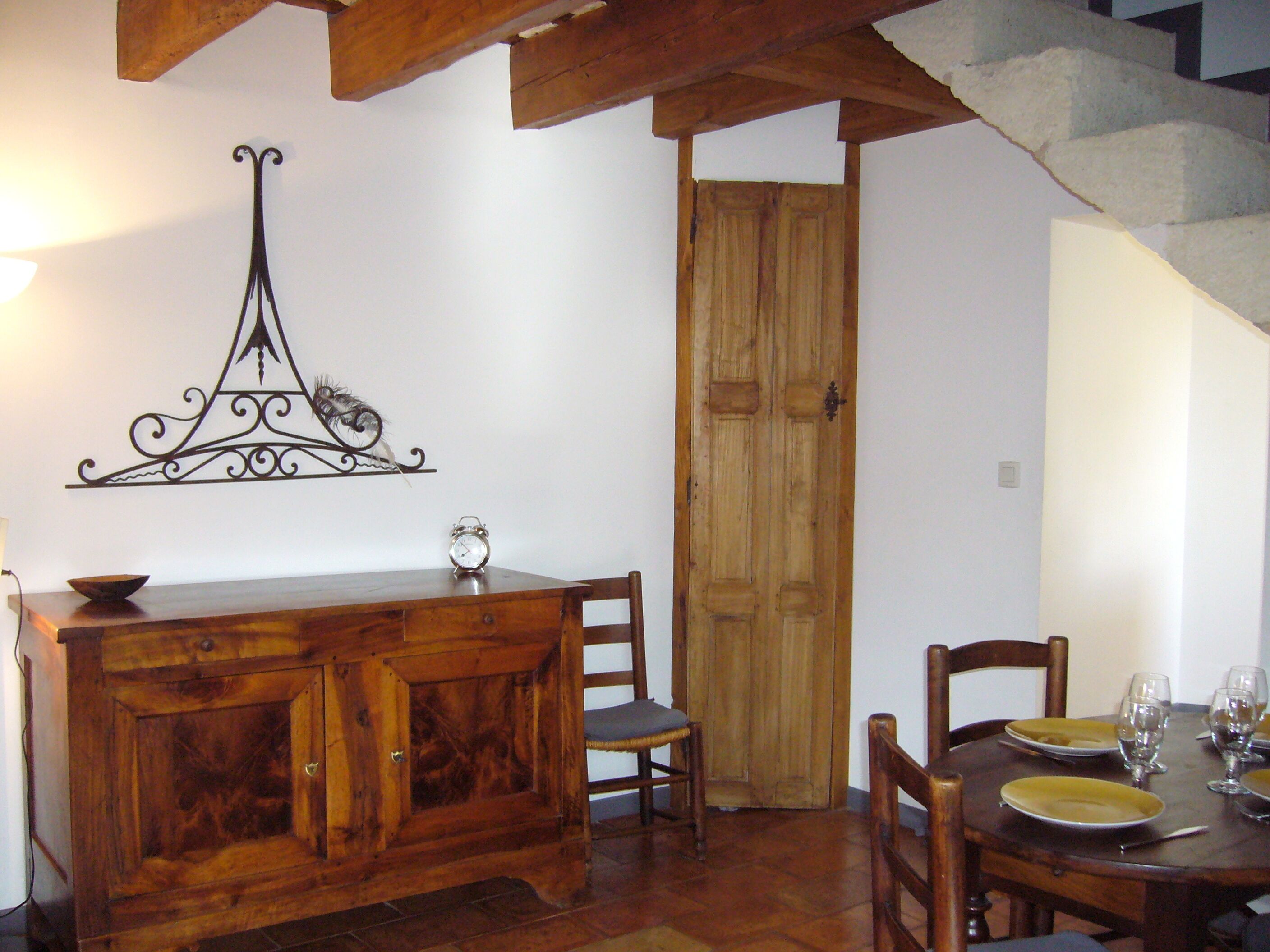 Un coin repas avec une table en bois dressée pour quatre personnes, un buffet en bois et un élément décoratif mural.