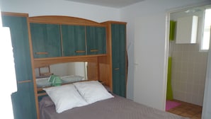 A single bed with a wooden headboard, a bedside table, and a green lamp. - apartment F1,1 room, 1 kitchen, 1 bathroom possibility 4 pers. (Vescovato)