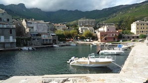 A harbor with boats docked, stone buildings, and a mountainous backdrop. - apartment F1,1 room, 1 kitchen, 1 bathroom possibility 4 pers. (Vescovato)