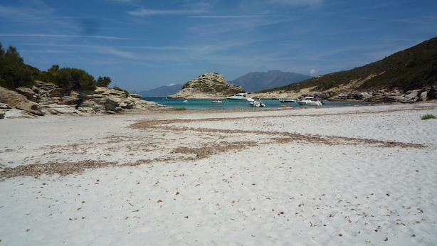 A beach with boats, rocky terrain, and mountains in the background. - apartment F1,1 room, 1 kitchen, 1 bathroom possibility 4 pers. (Vescovato)