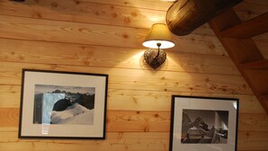 Et træloft med en vægmonteret lampe og to billeder i rammer af bjerge.
