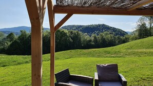 A wooden pergola with a view of a green hillside and a mountain in the background.