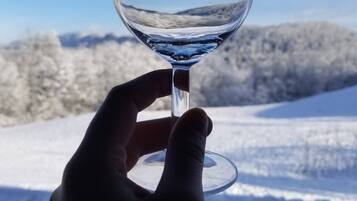 Eine Hand hält ein Glas mit verschneiter Landschaft im Hintergrund.