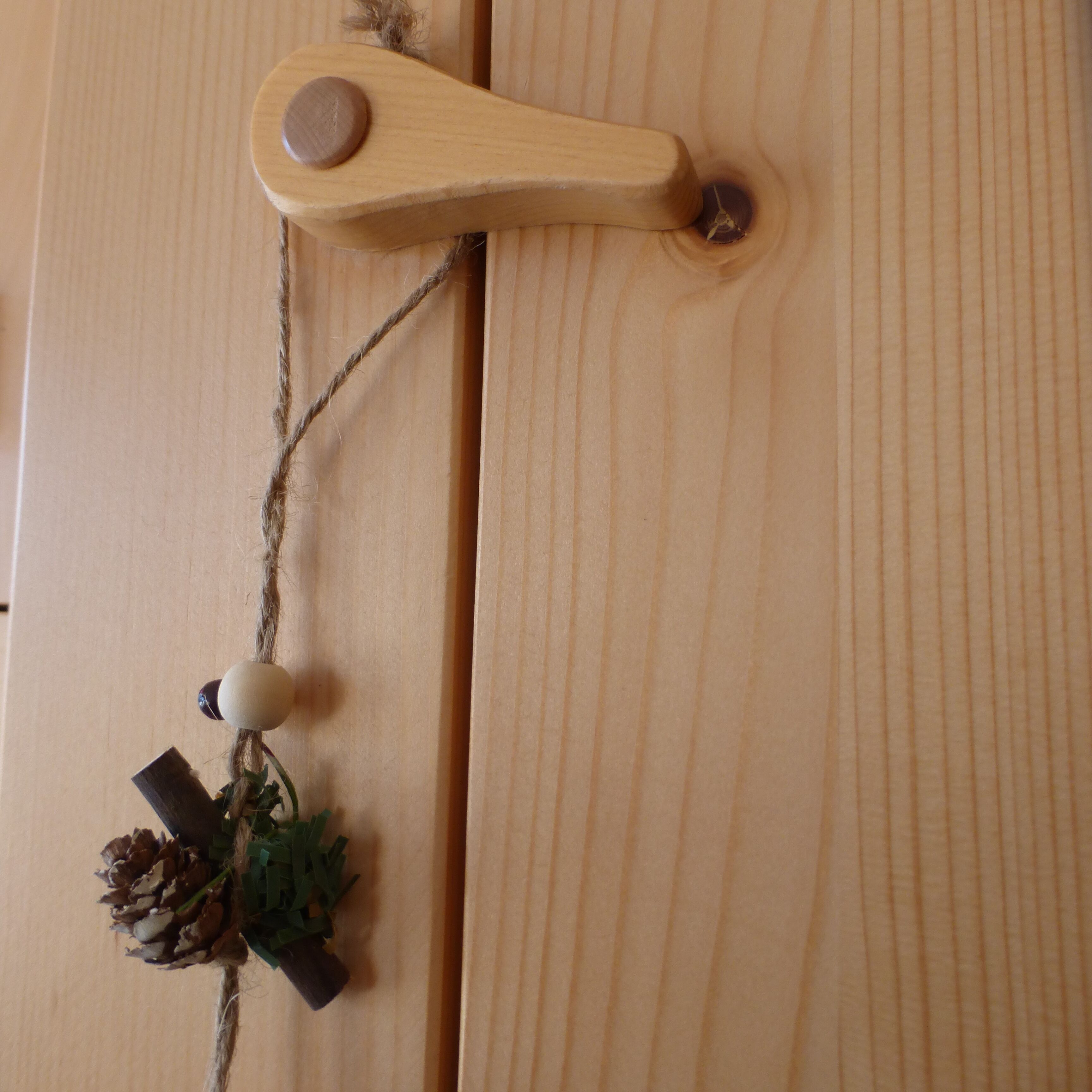 Una puerta de madera con un pomo sencillo y rústico, y un adorno pequeño colgando del pomo.
