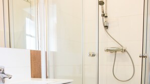 A bathroom with a glass-enclosed shower, a white sink, and a wooden countertop. - Sopot Sleeps - Sopot Suite (Sopot)