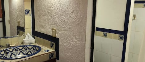 A bathroom with a white sink, blue and white tiles, a mirror, and a white toilet.