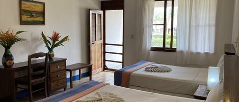 A hotel room with two beds, a desk, and a chair. There is a painting on the wall, a window with curtains, and a door leading outside.