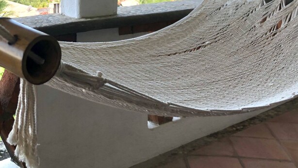 Un hamac sur un balcon avec vue sur la plage et l’océan.