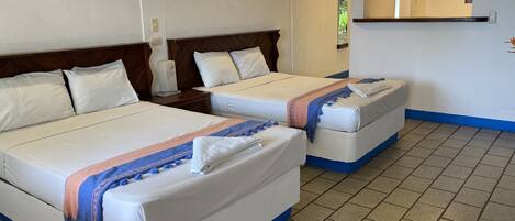 A hotel room with two beds, a wooden headboard, a small nightstand, and a mirror above the bed.