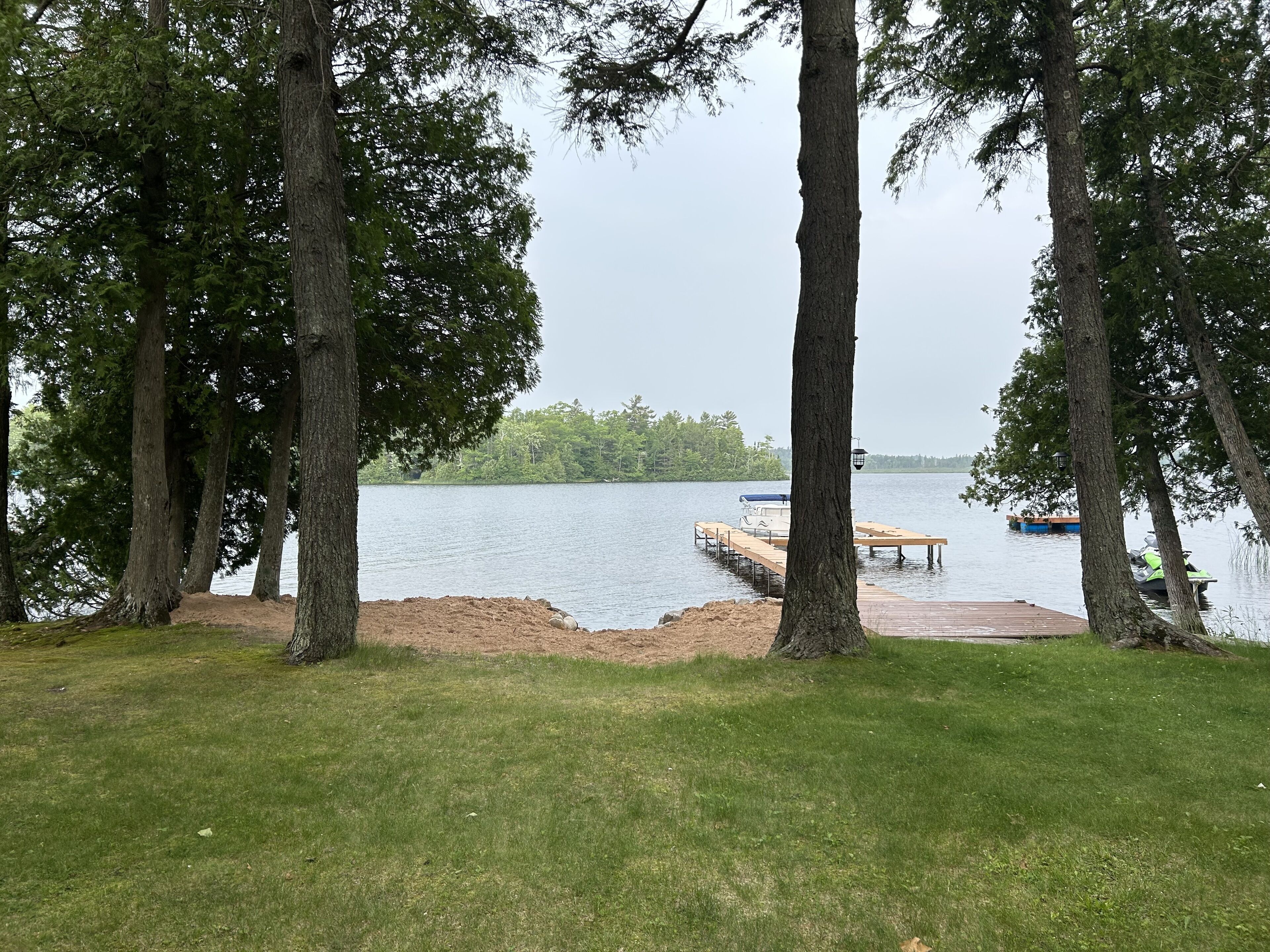 A lakeside view with a dock extending into the water, surrounded by trees.