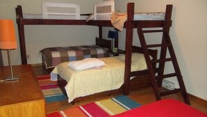 A bunk bed room with a desk, a lamp, and a colorful rug.