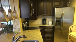 Cocina con encimeras de granito, electrodomésticos de acero inoxidable y armarios de madera oscura.