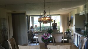 Comedor con candelabro, sillas de madera y una mesa con un jarrón de flores.