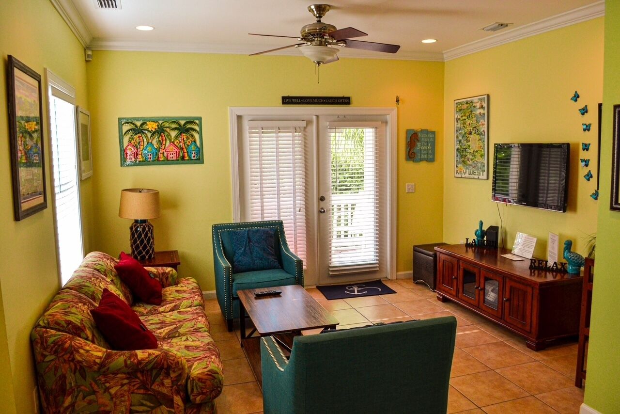 A living room with a sofa, armchair, coffee table, and a cabinet with decorative items.