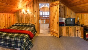 A wooden cabin room with two beds, a television, and a door leading to a balcony. - Sun Mountain Ranch Bunkhouse - Near Crater Lake (Fort Klamath)